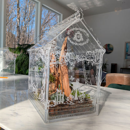 Side view of the Victorian-inspired terrarium featuring an engraved tent scene, adding a whimsical touch to the lush plant display with moss, ferns, and delicate details.